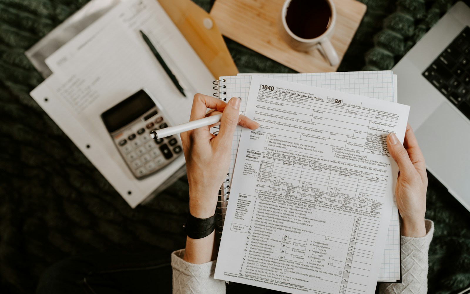 Financial documents being reviewed with a calculator and laptop