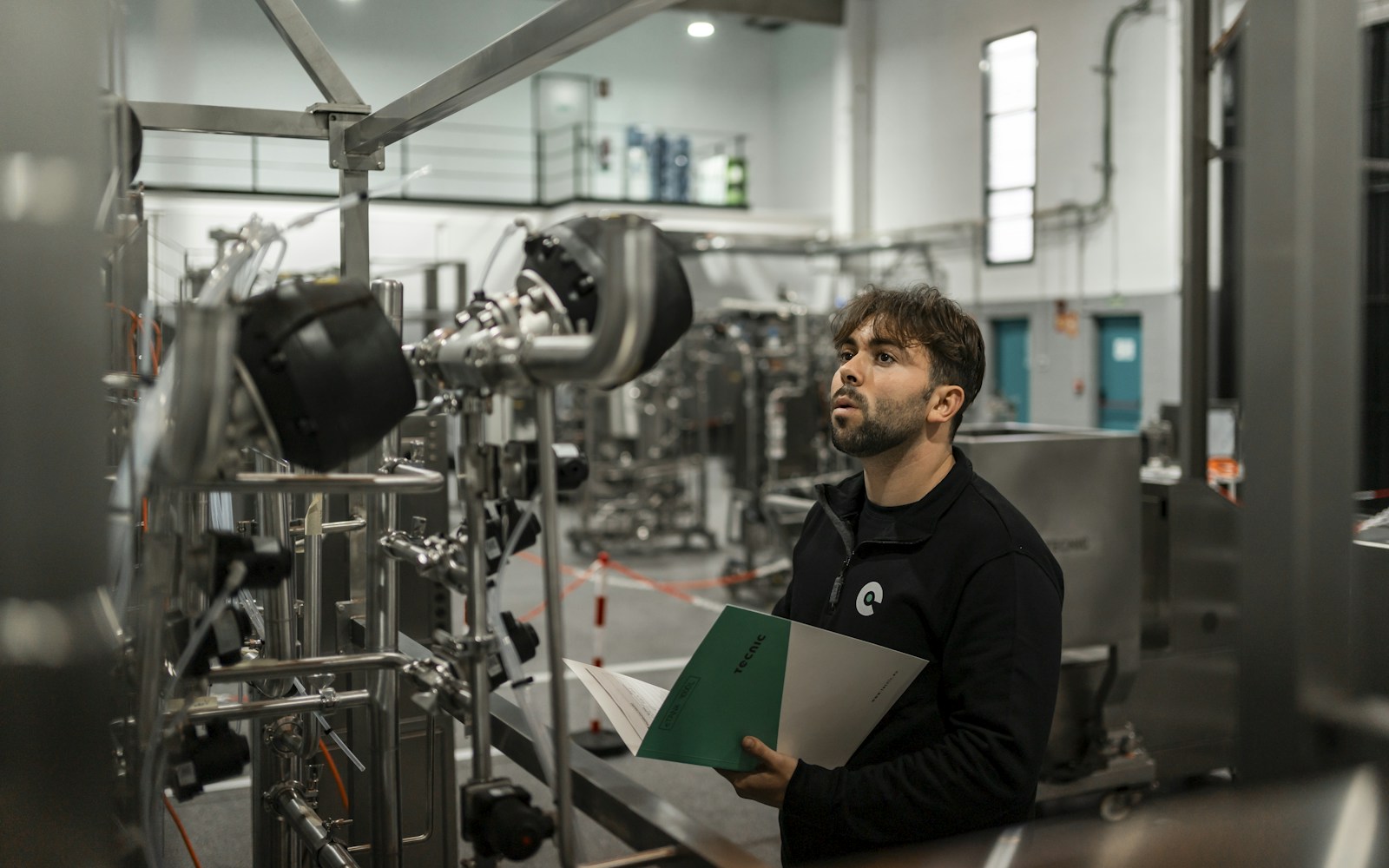 Technician inspecting industrial equipment with documentation