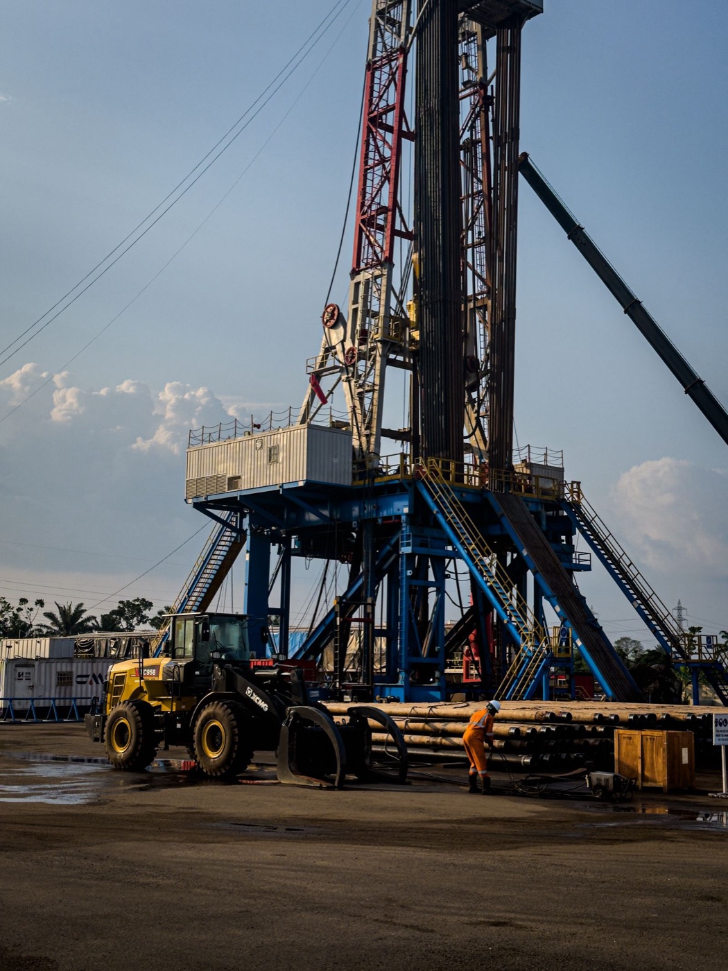 Oilfield service crew working beside a drilling rig and field equipment